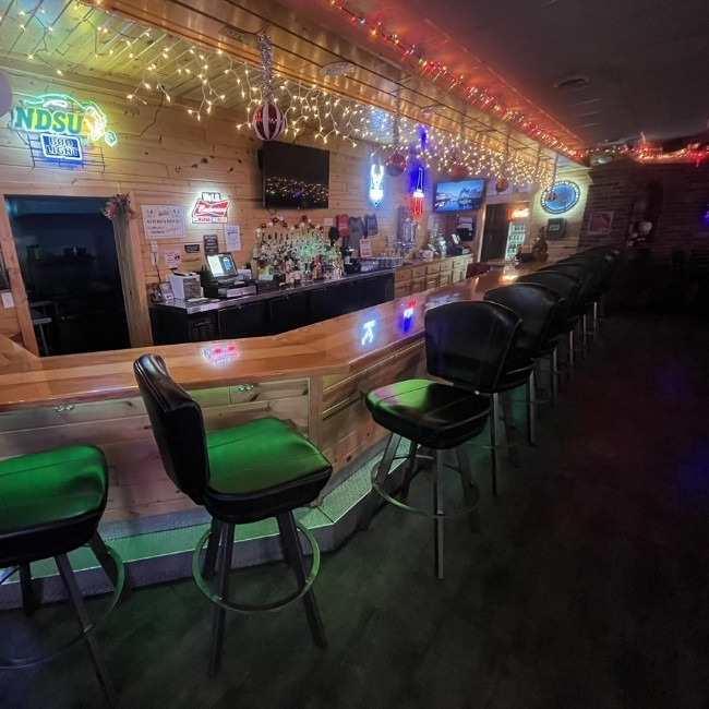 A cozy spot at The Hill Bar & Grill in Glyndon MN with neon signs and a wooden counter.
