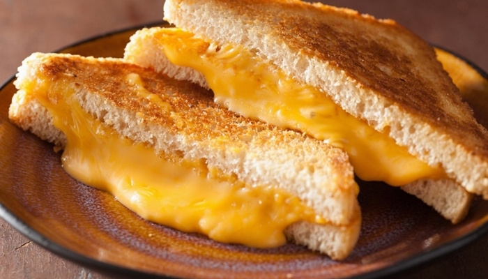 Two halves of grilled cheese with melted cheese on a brown plate—Restaurant Menu Glyndon MN.