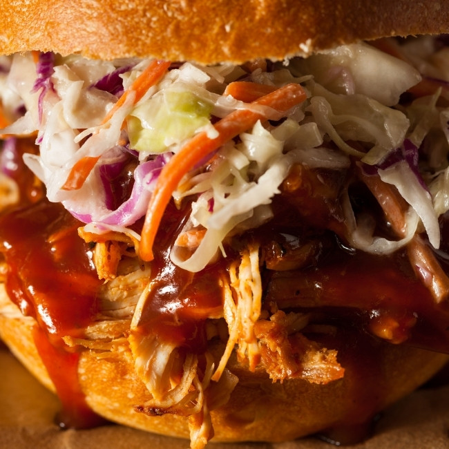 Close-up of a pulled pork sandwich at a top restaurant in Glyndon MN, with BBQ sauce and coleslaw.
