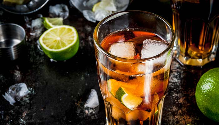 A glass of iced cocktail with lime at a Bar in Glyndon MN, surrounded by ice and lime pieces.